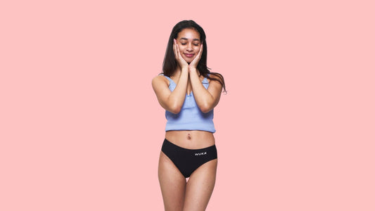Picture of young woman against a pink background wearing a pair of WUKA period pants